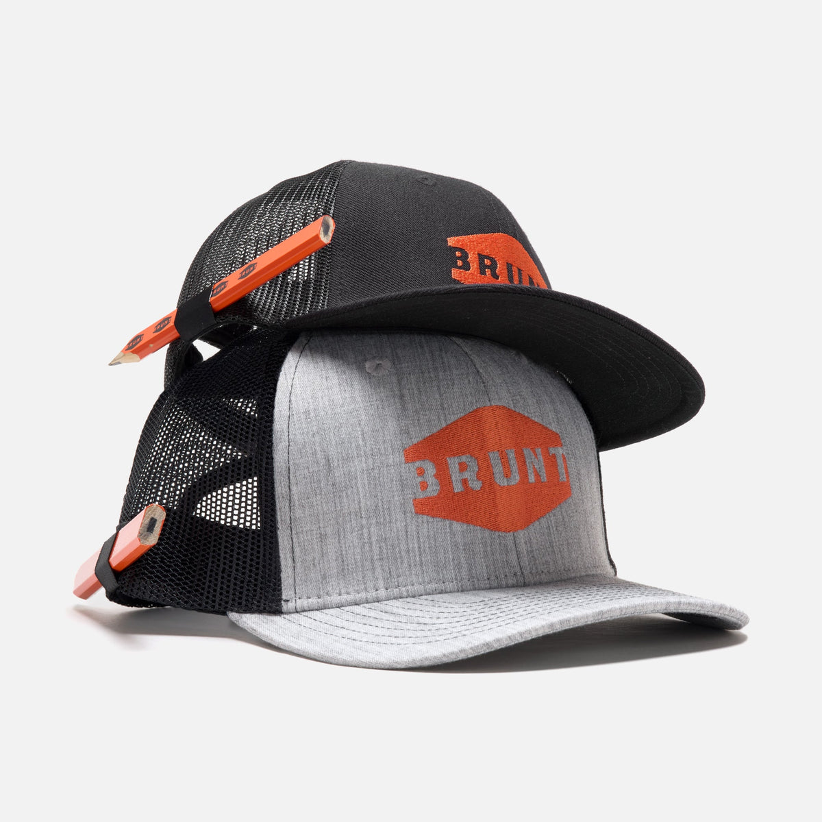 Kids flat brim hat in black sitting on curved brim work hat with built in pencil holder and BRUNT logo in grey