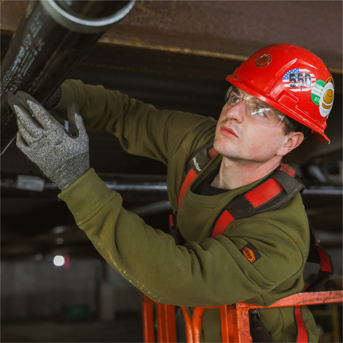 Man on jobsite wearing the BRUNT water resistant midweight crewneck in hunter green