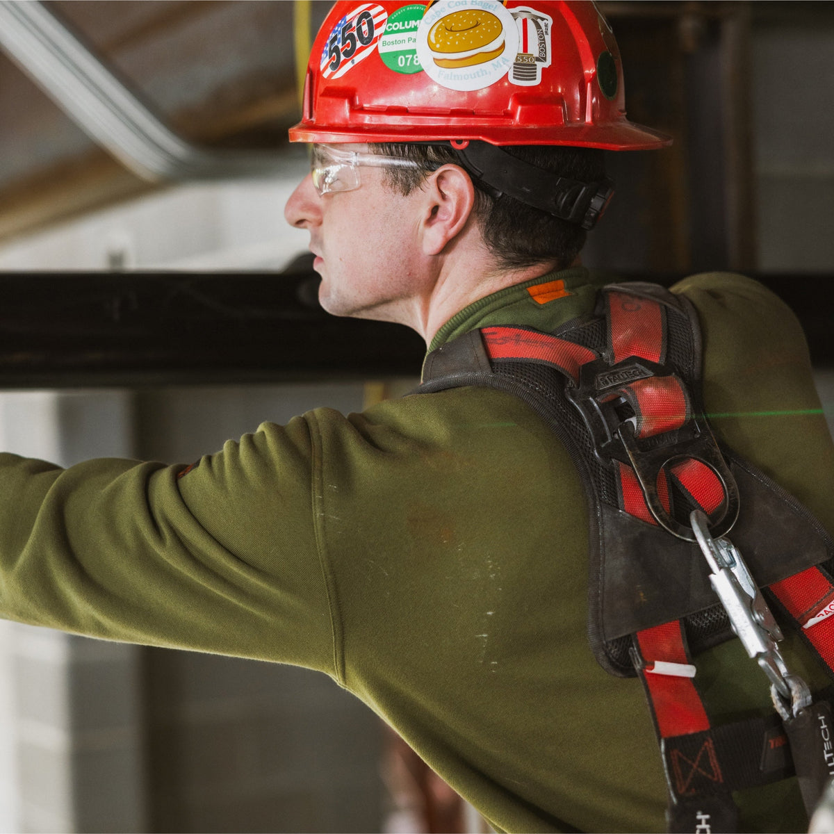Man on jobsite wearing the BRUNT water resistant midweight crewneck in hunter green