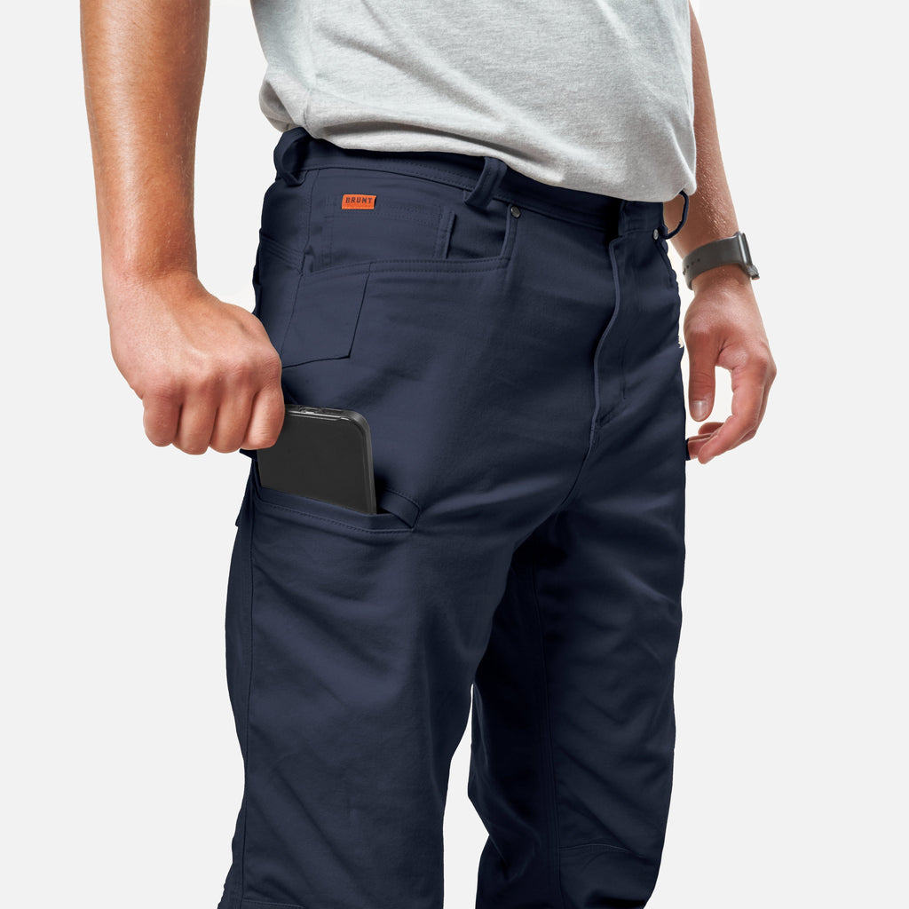 View 2 putting phone in tech pocket of BRUNT water resistant stretch torra work pant in dark navy * 0