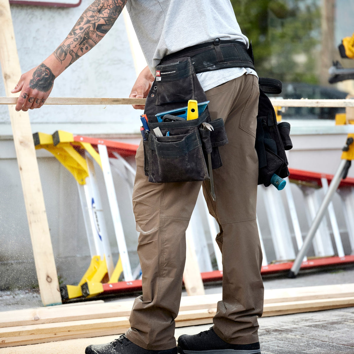 Man on jobsite wearing BRUNT water-resistant lightweight breathable costello work pant in brown