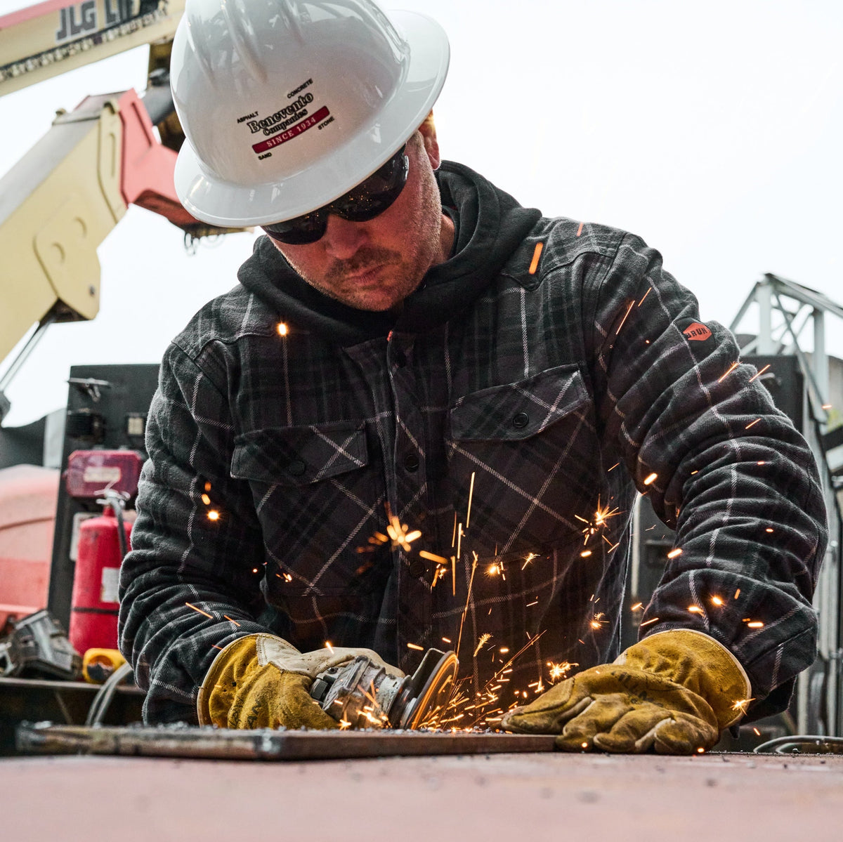 Man on jobsite wearing the BRUNT quilted flannel work jacket in charcoal and black plaid