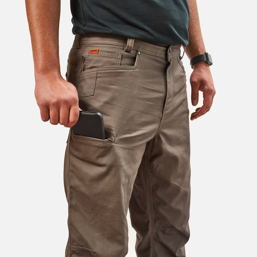 View 2 putting phone in tech pocket of BRUNT water resistant stretch torra work pant in brown * 4