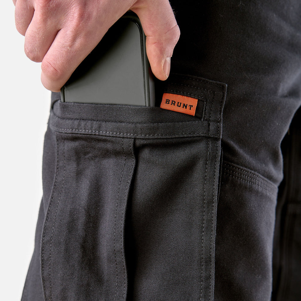 View 2 putting phone in cargo pocket of BRUNT water resistant double knee cargo pants in black * 1