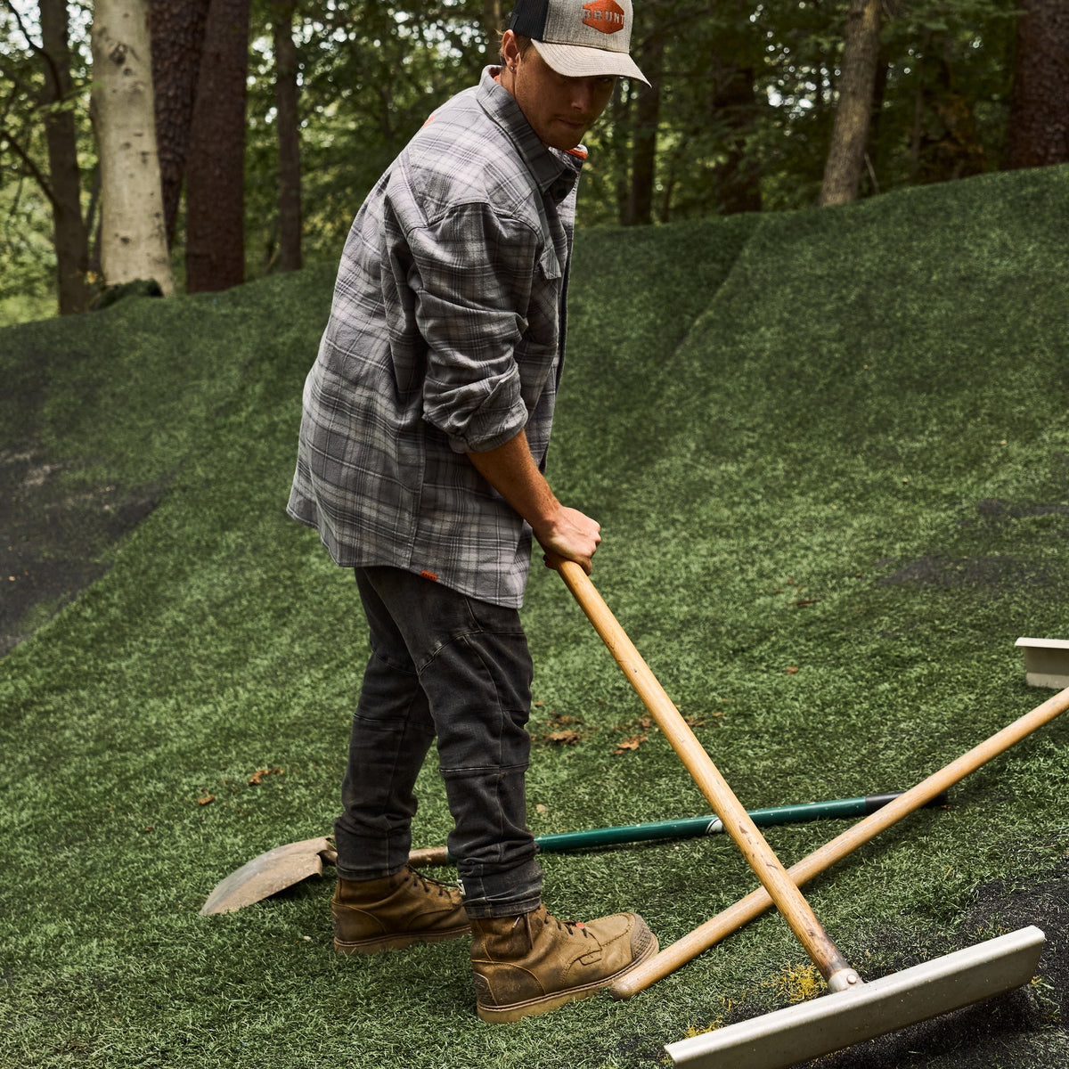 Man in BRUNT heavy duty stretch work flannel in light grey plaid holding circular saw at jobsite