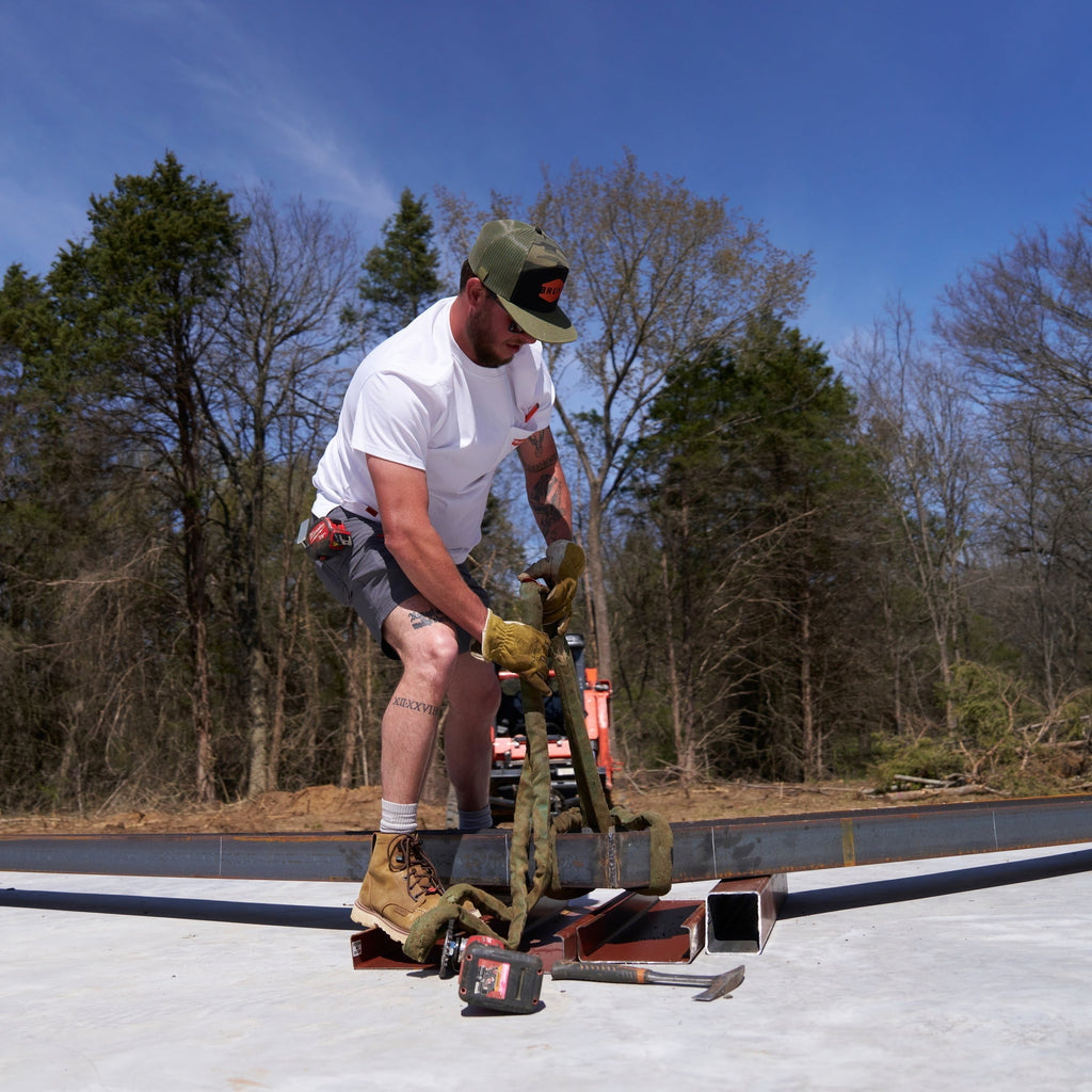 Man on jobsite wearing BRUNT 9 inch lightweight breathable costello work shorts in charcoal