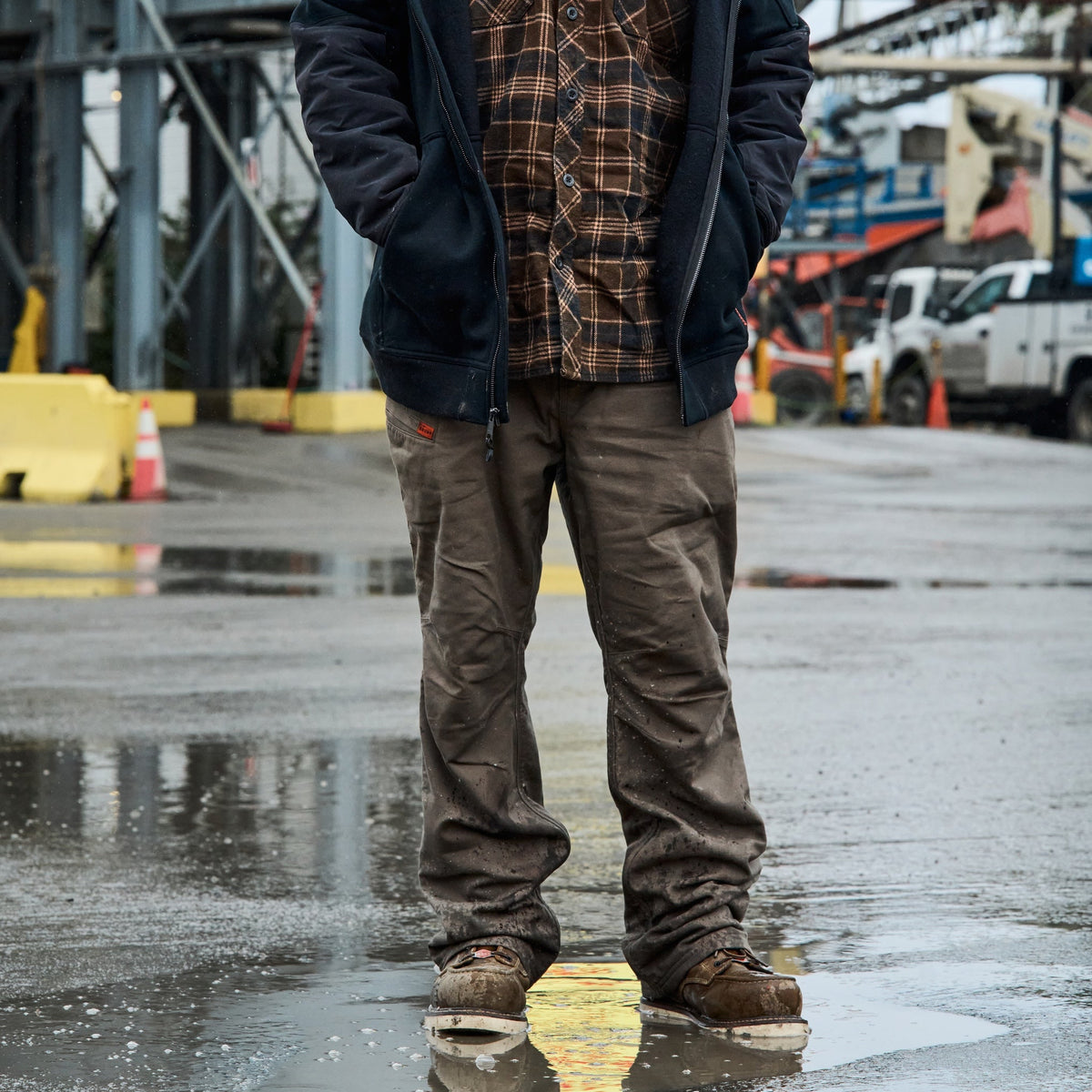 Man on jobsite wearing the BRUNT water resistant stretch torra work pant in brown