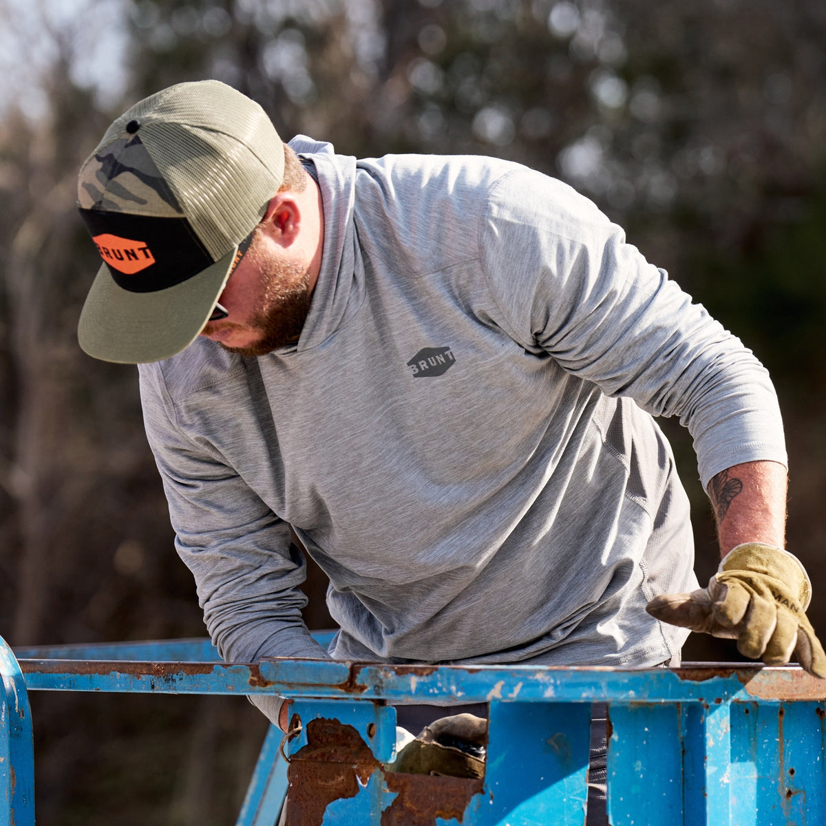 Man on jobsite wearing BRUNT lightweight mckenna sun hoodie with UPF protection in grey heather