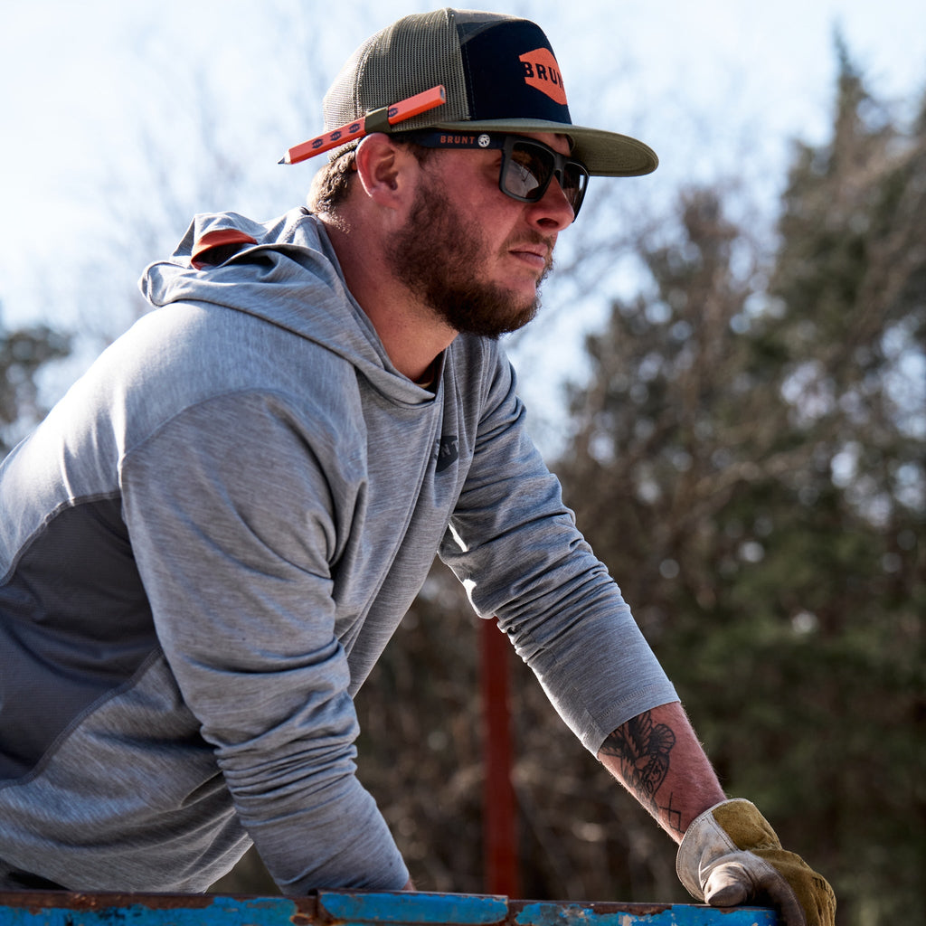 Man on jobsite wearing BRUNT lightweight mckenna sun hoodie with UPF protection in grey heather