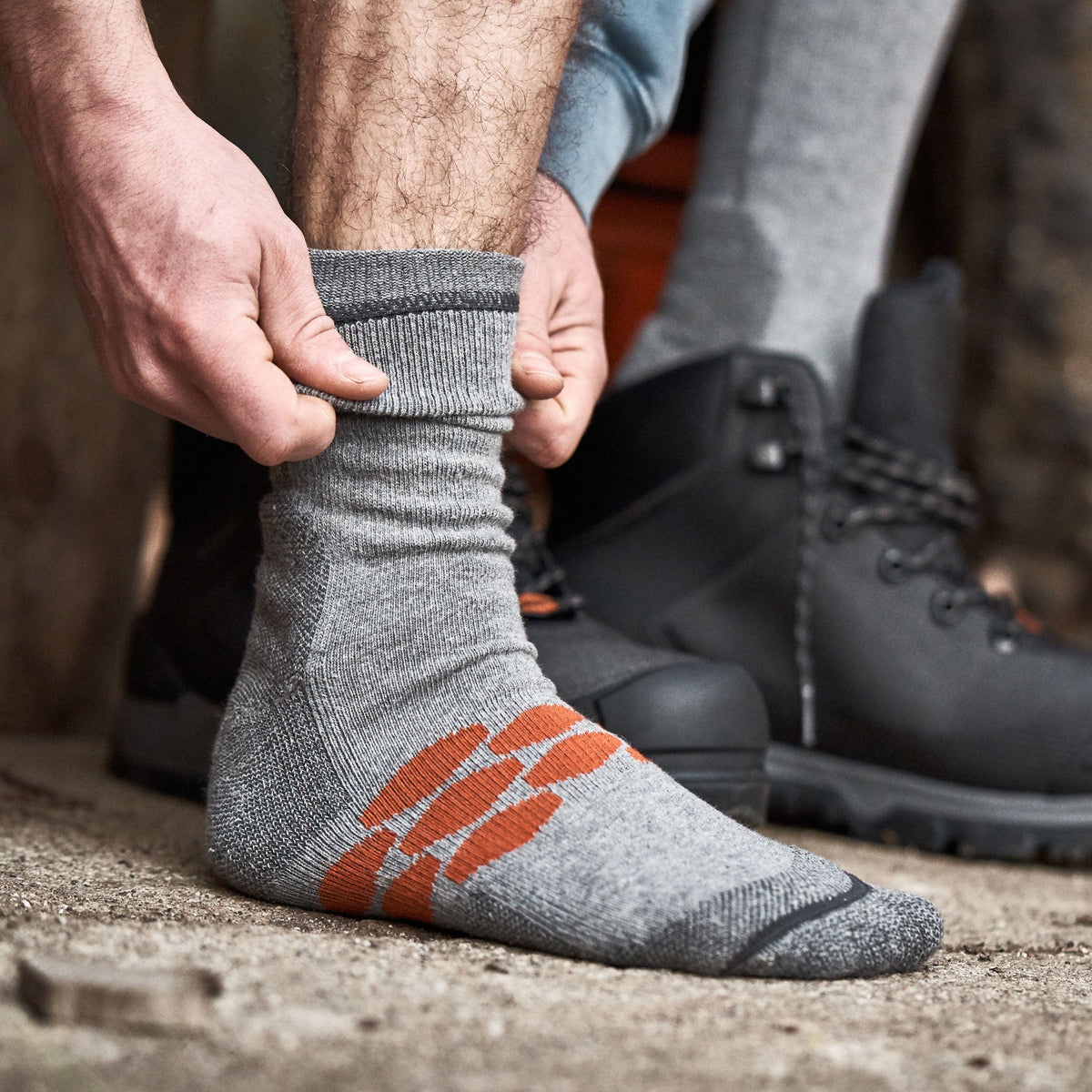View 2 man putting on high quality, durable performance socks with BRUNT logo in grey * 0