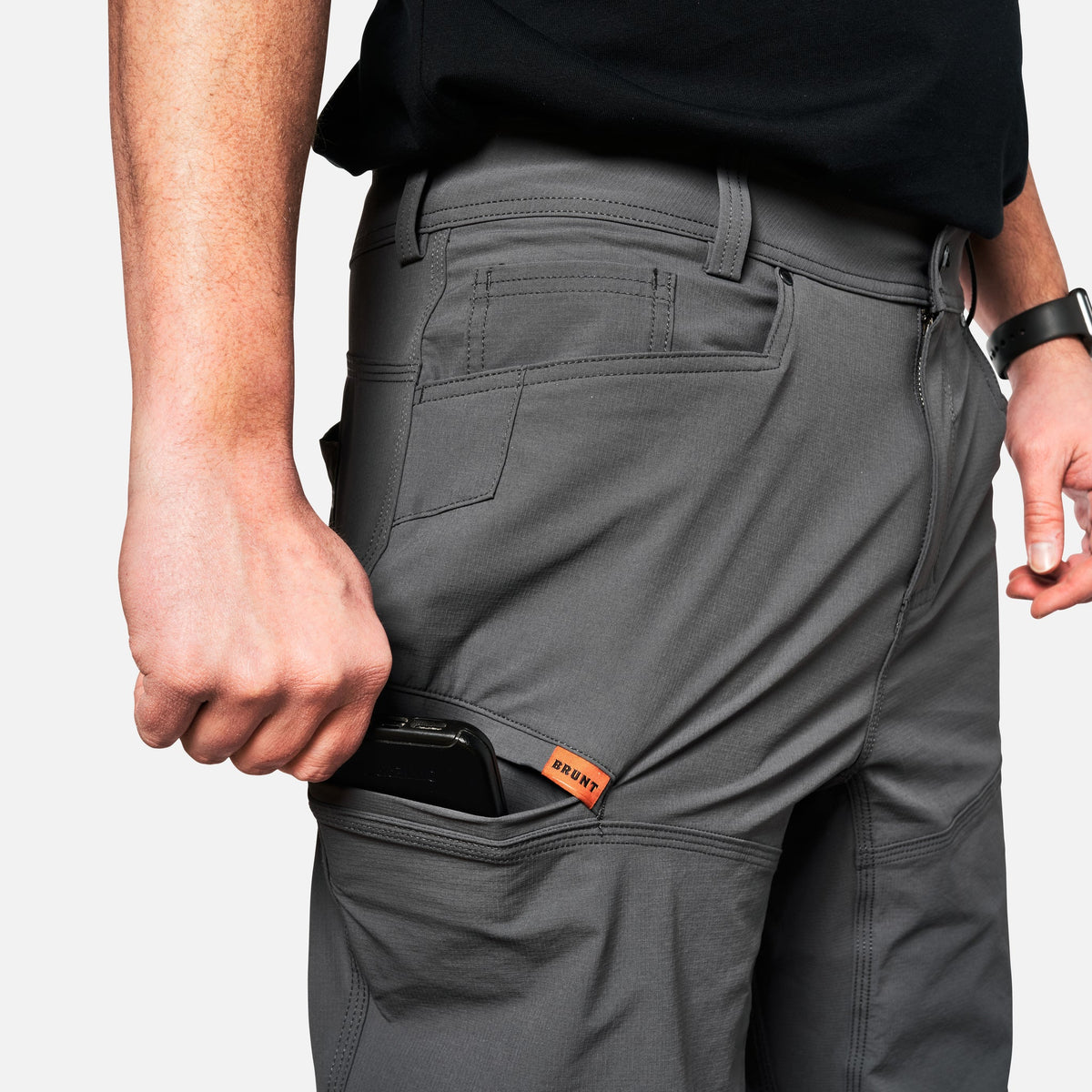 Putting phone in tech pocket of BRUNT water-resistant lightweight lined costello work pant in charcoal