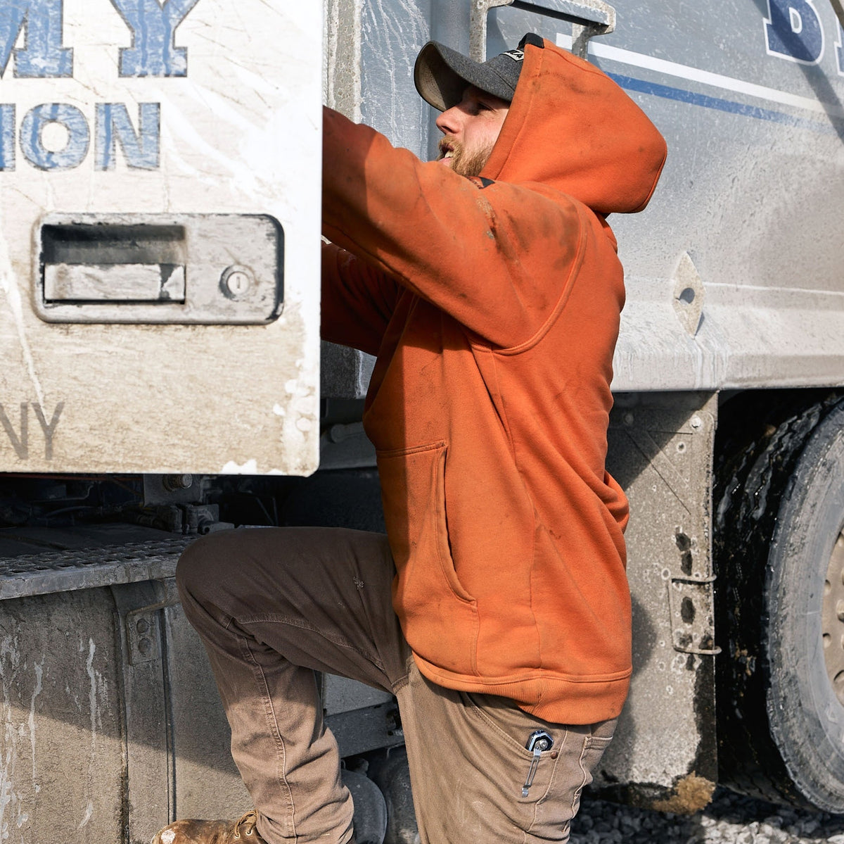 Man on jobsite wearing the BRUNT water resistant shevlin work hoodie in BRUNT orange