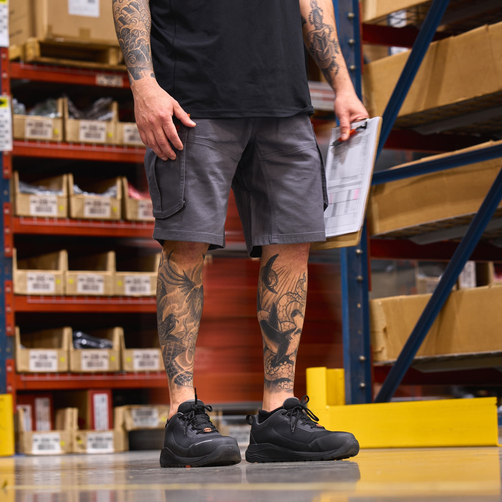 Man wearing BRUNT abrasion resistant cargo work shorts in charcoal in warehouse