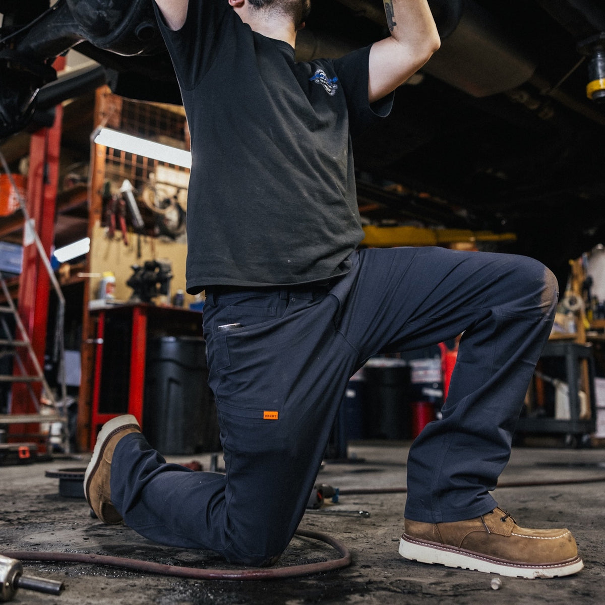 Man on jobsite wearing the BRUNT water resistant stretch torra work pant in dark navy