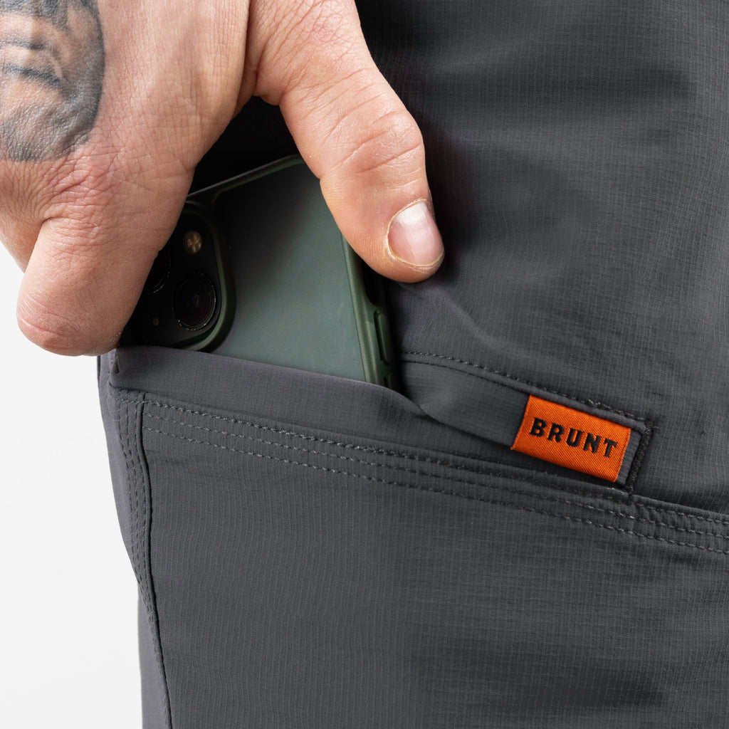 Putting phone in tech pocket of BRUNT 9 inch lightweight breathable costello work shorts in charcoal