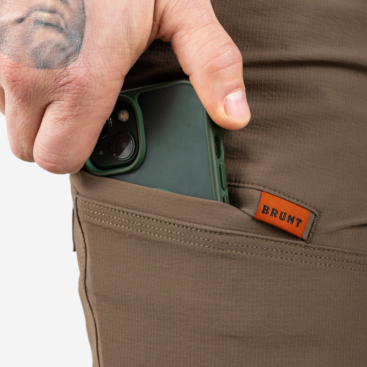 Putting phone in tech pocket of BRUNT 11 inch lightweight breathable costello work shorts in brown