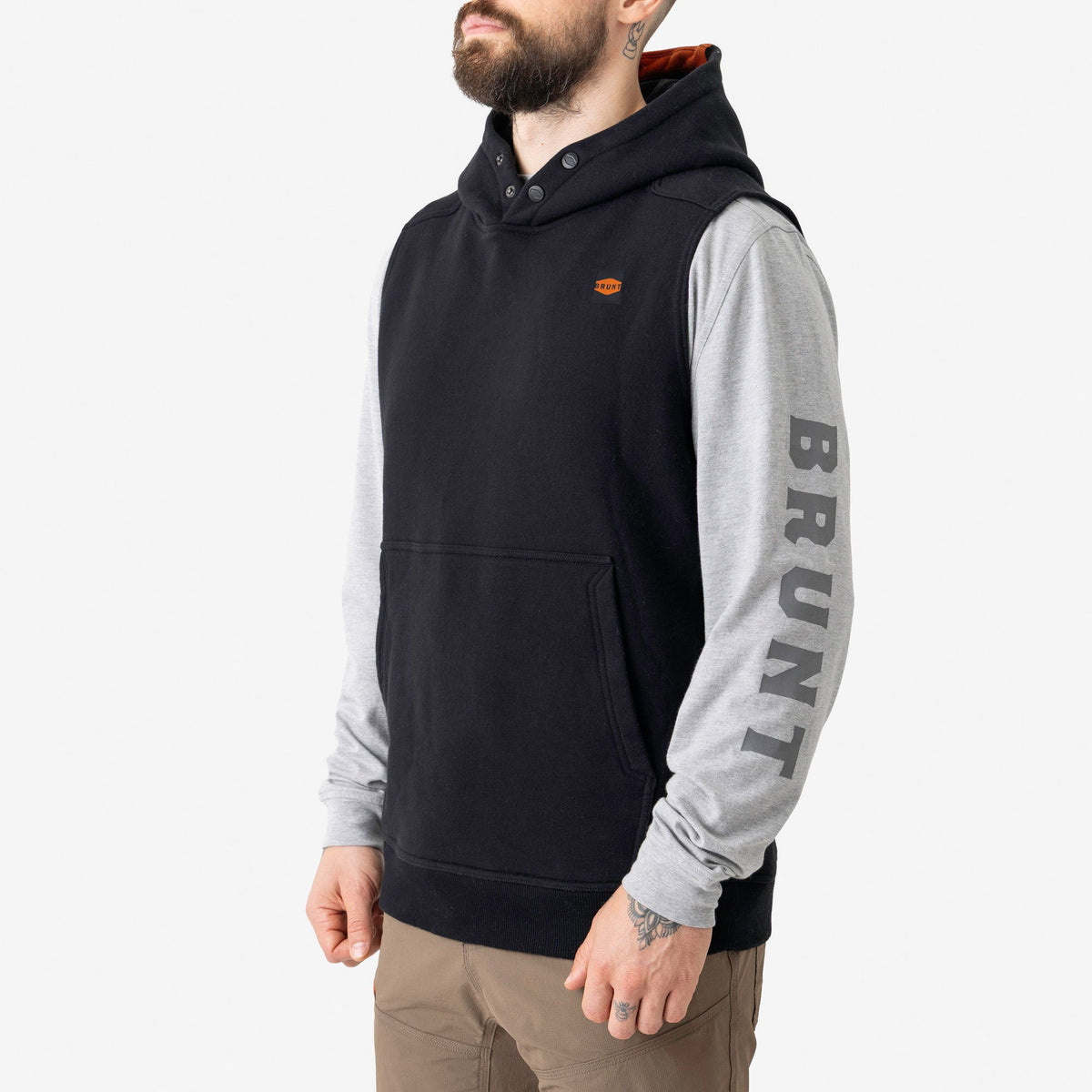 45 degree angle of the left side of the BRUNT sleeveless water resistant workwear hoodie in black with BRUNT high quality long sleeve pocket tee in light grey underneath