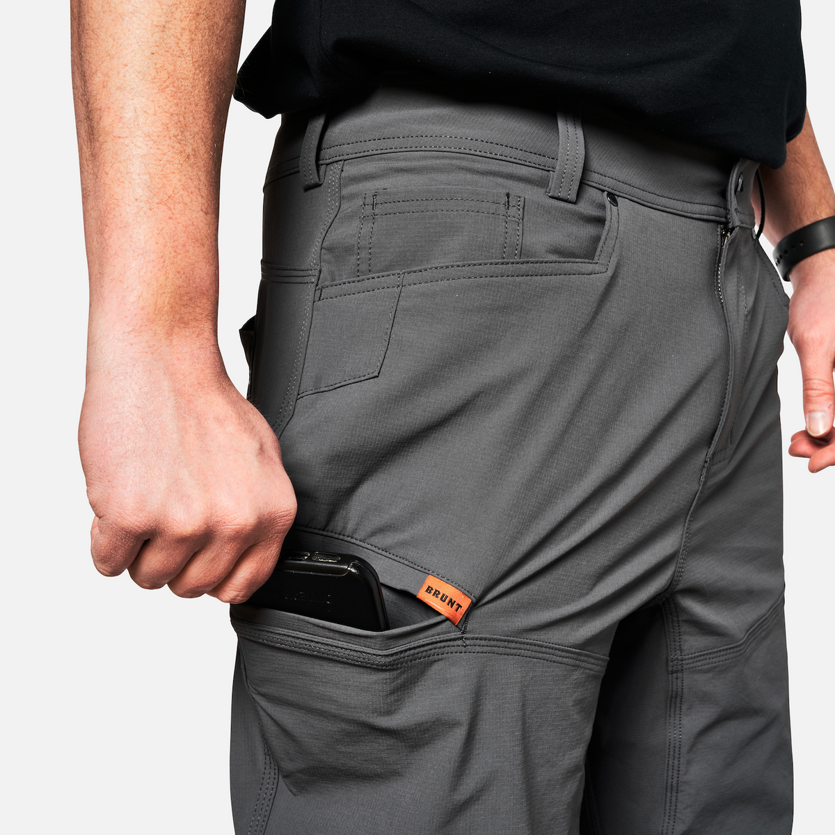 Putting phone in tech pocket of BRUNT water-resistant lightweight breathable costello work pant in charcoal * 1