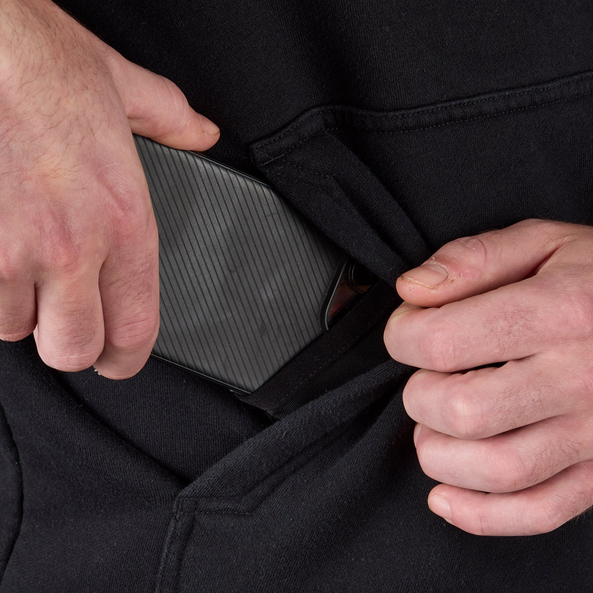 Front of hand pocket with man putting phone in tech pocket of the BRUNT heavyweight water-resistant workwear hoodie in black