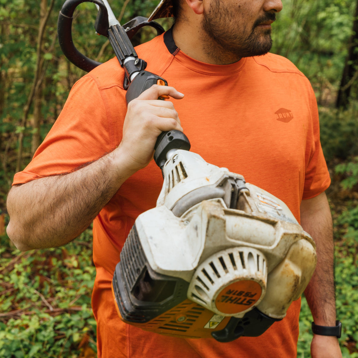 Man wearing BRUNT lightweight mckenna sun tee with UPF protection in BRUNT orange while holding a weed whacker on shoulder * 0